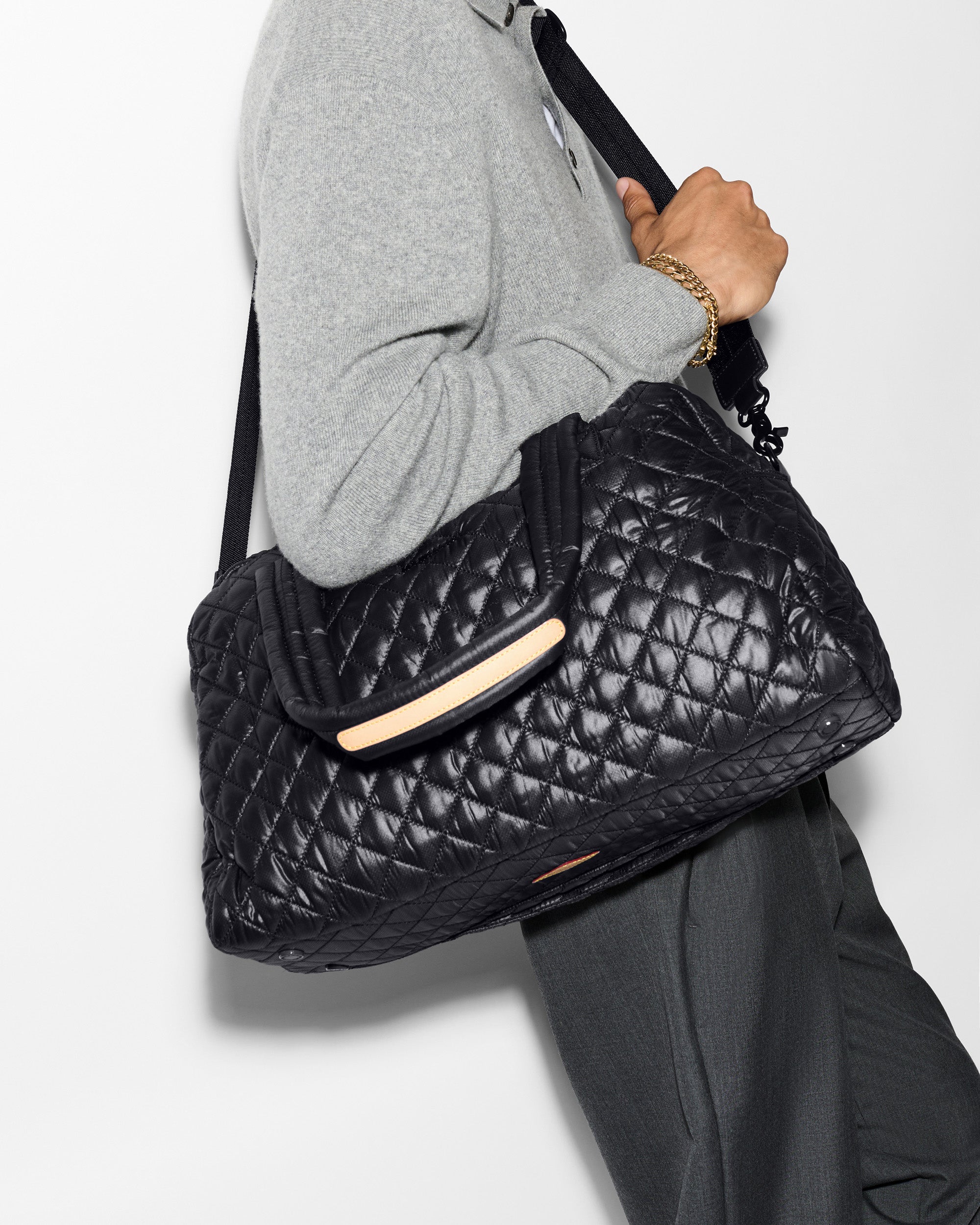 Man holding MZ Wallace Black Quilted Duffle Travel Bag on shoulder