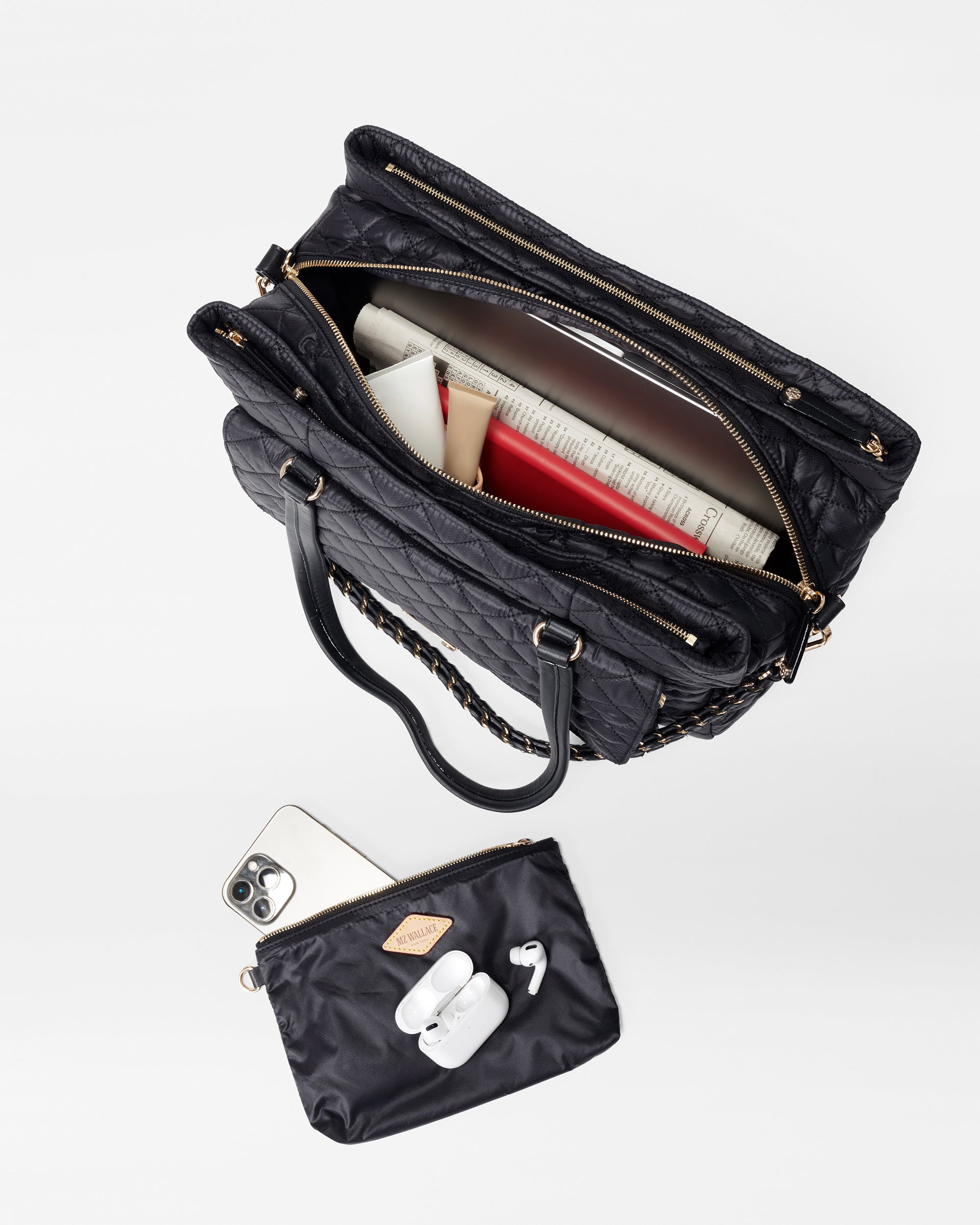 Top view of MZ Wallace Black Structured Work Bag filled with different items, a phone, airpods on top of accessory bag